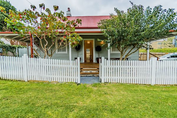 Hindmarsh Park Cottage exterior — grey weatherboard, red roof, white picket fence
