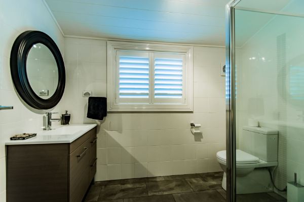 Modern bathroom with oval mirror and plantation shutters